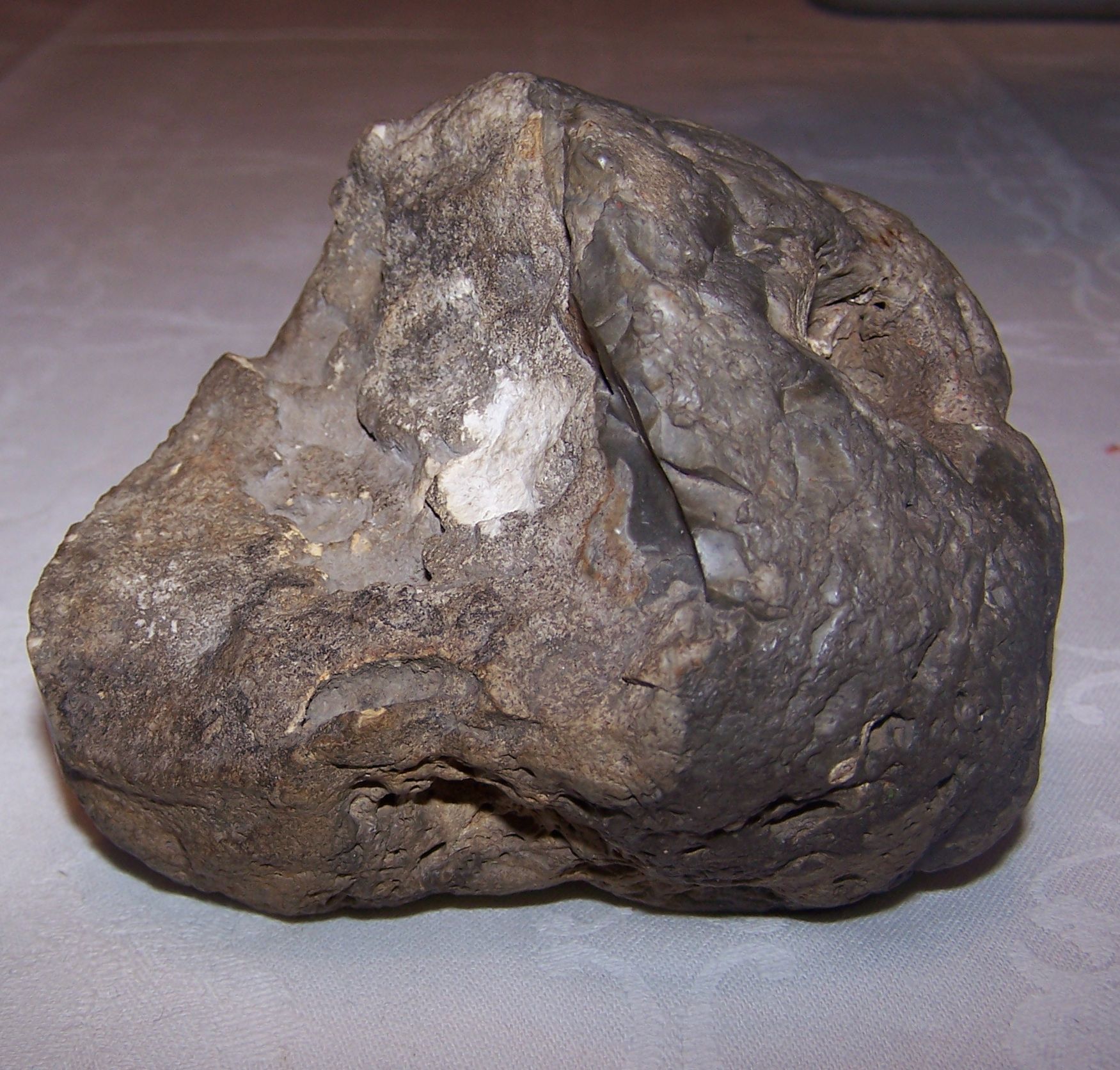 Der Meteorit wurde bei Ausschachtungsarbeiten in ~ 50cm Tiefe in gewachsenen Boden gefunden.
Er wog 900g, ist nicht magnetisch und hat eine Wichte von 2,2g/cm³ 
An dem Meteoriten sind Brandspuren unverkennbar. Daher lässt sich das fehlende Stück vorne zuordnen. Das Abbruchstück kann der Meteorit nur beim Aufschlag auf dem Erdboden verloren haben, denn die zu sehende Abbruchfläche zeigt keine Brandspuren, sondern nur eine Verwitterungskruste nach einem bestimmt jahrelangen Aufenthalt im Erdboden.